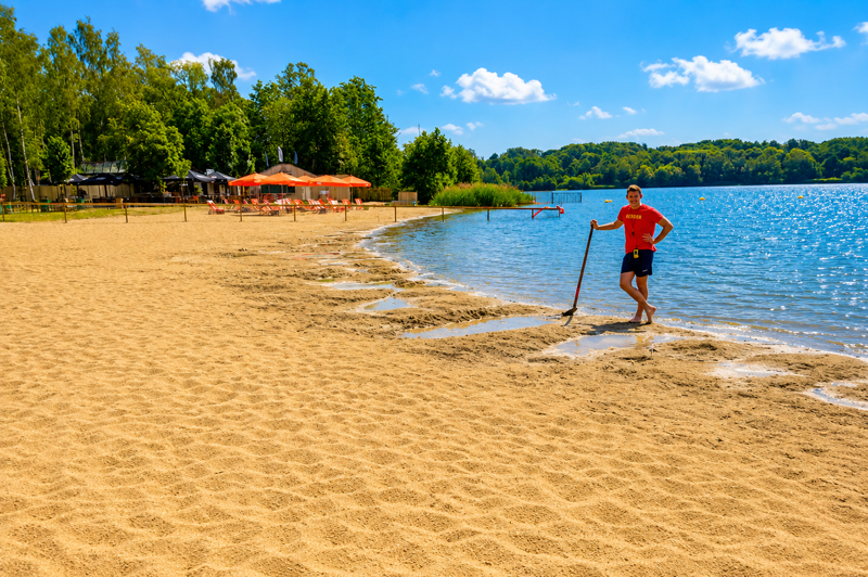 Lifeguard maintaining the sandy beach at De Plas in Rotselaar before visitors arrive