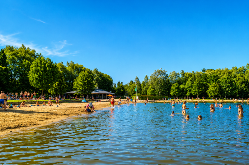 Panoramic view of De Plas beach in Rotselaar with families enjoying the sandy beach and swimming area